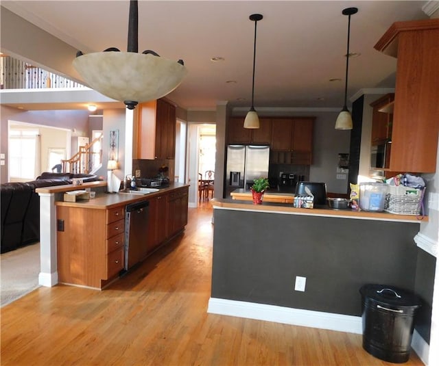 kitchen with kitchen peninsula, hanging light fixtures, light hardwood / wood-style floors, and appliances with stainless steel finishes