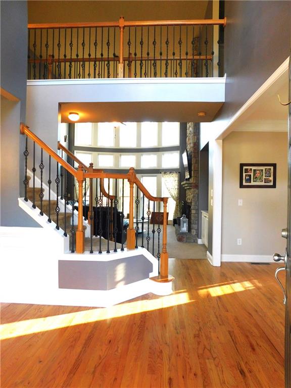 staircase with a high ceiling, a large fireplace, crown molding, and hardwood / wood-style floors