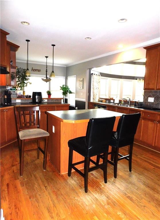 kitchen featuring a kitchen bar, decorative backsplash, light wood-type flooring, pendant lighting, and a kitchen island