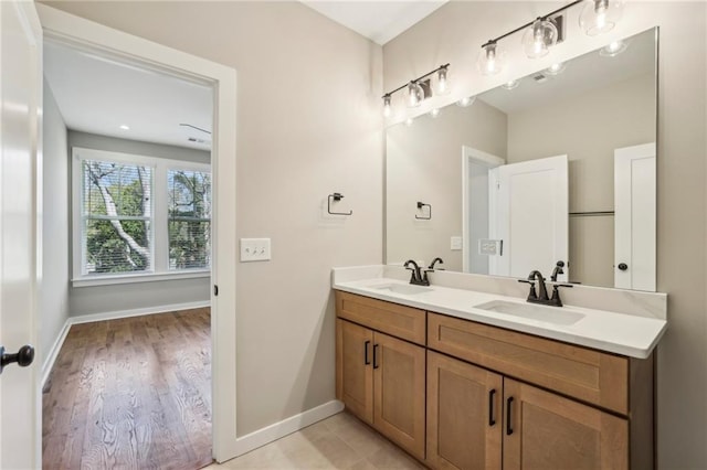 bathroom featuring baseboards, double vanity, and wood finished floors