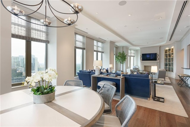 dining space featuring wood-type flooring, plenty of natural light, and a notable chandelier