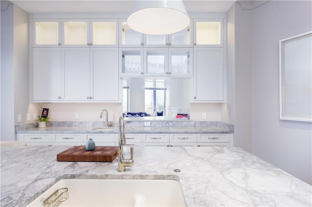 kitchen featuring light stone countertops, sink, and white cabinets