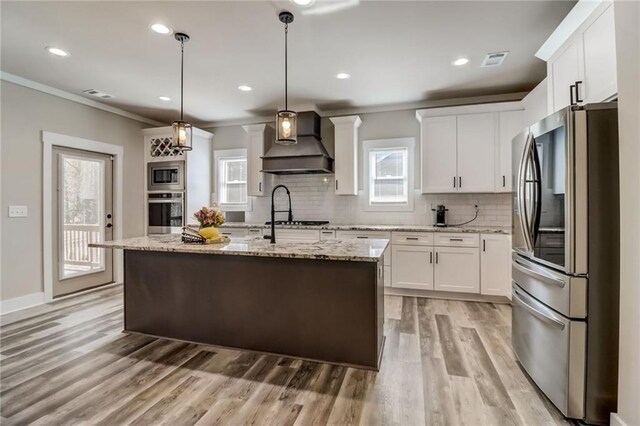 569 White Oak Way, Monroe, GA 30655 - kitchen featuring a kitchen island with sink, wall chimney exhaust hood, decorative light fixtures, and appliances with stainless steel finishes