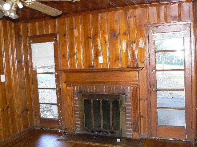 details featuring a brick fireplace, wooden walls, and wood finished floors