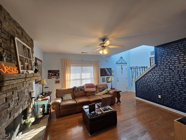 living room with a stone fireplace, hardwood / wood-style floors, and ceiling fan