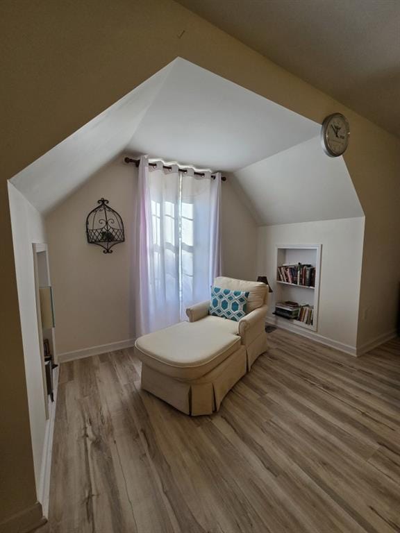 bonus room featuring lofted ceiling, built in shelves, and wood-type flooring