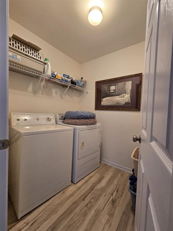 washroom featuring washing machine and clothes dryer and light hardwood / wood-style flooring