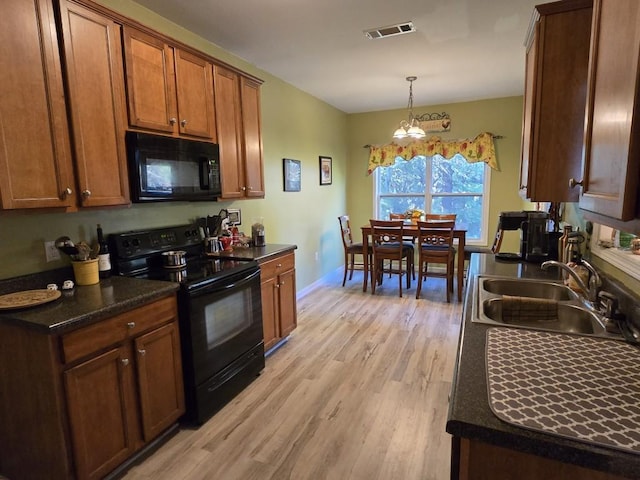 kitchen with pendant lighting, sink, black appliances, light hardwood / wood-style floors, and dark stone counters