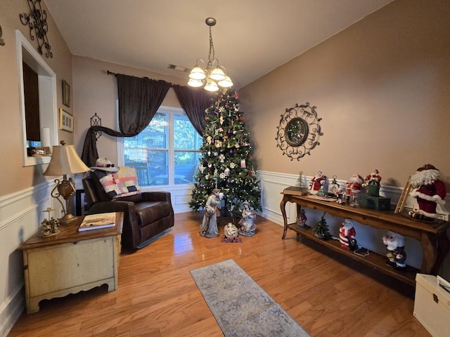 sitting room featuring an inviting chandelier, lofted ceiling, and light wood-type flooring