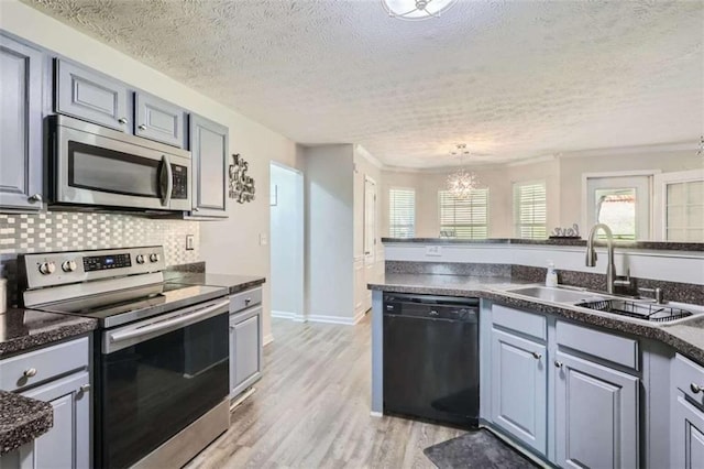 kitchen with sink, stainless steel appliances, tasteful backsplash, decorative light fixtures, and light wood-type flooring