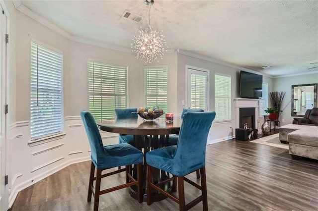 dining space featuring crown molding, an inviting chandelier, and dark hardwood / wood-style flooring