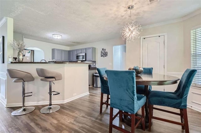 dining room featuring a notable chandelier, dark wood-type flooring, and a textured ceiling