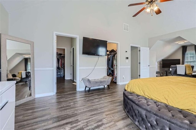 bedroom with a spacious closet, dark wood-type flooring, high vaulted ceiling, and a closet