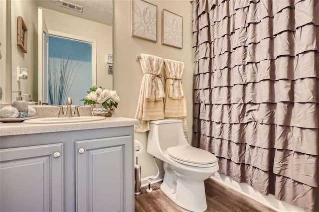 full bathroom with shower / bath combo, hardwood / wood-style floors, vanity, a textured ceiling, and toilet