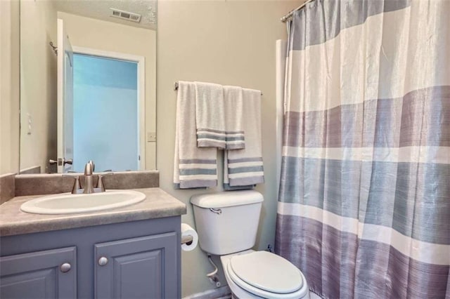 bathroom featuring vanity, curtained shower, and toilet