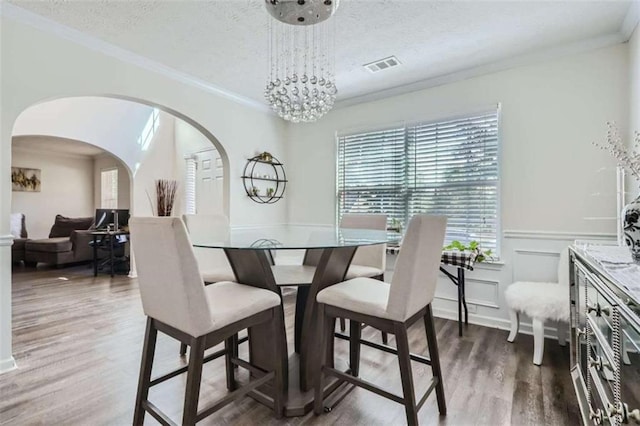 dining space with an inviting chandelier, ornamental molding, dark hardwood / wood-style flooring, and a textured ceiling