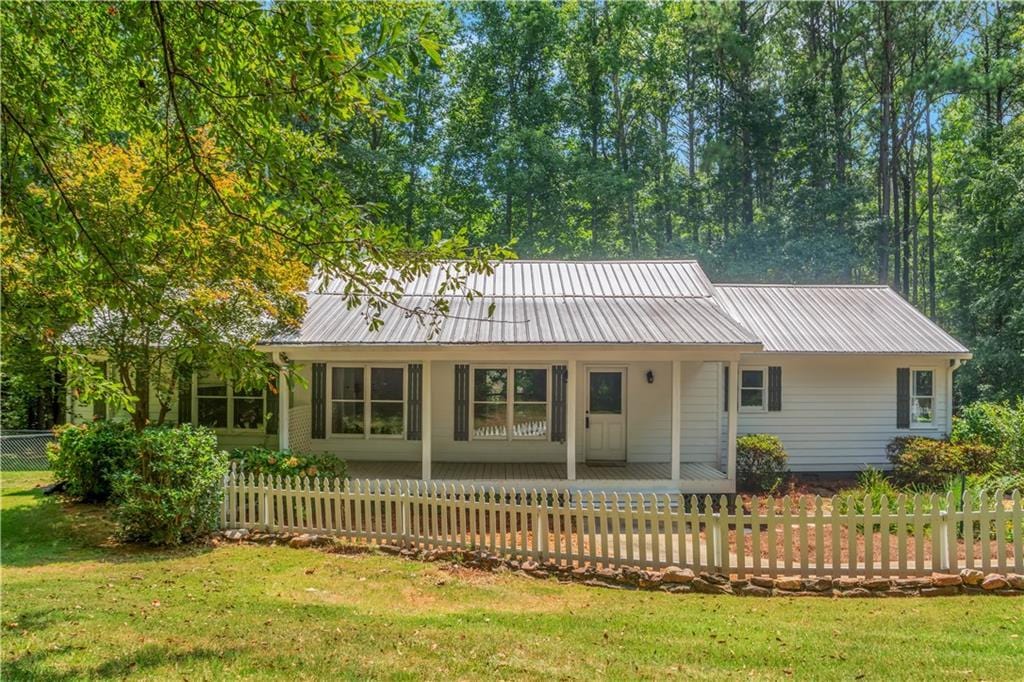 single story home featuring a fenced front yard, metal roof, and a front yard