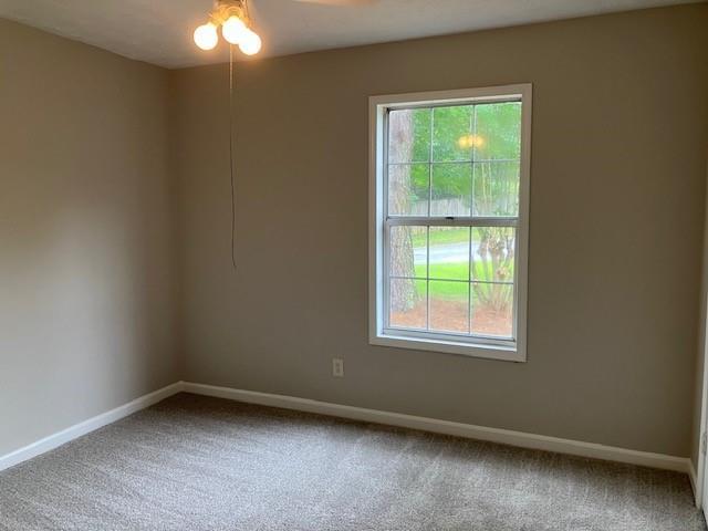 unfurnished room with ceiling fan and carpet