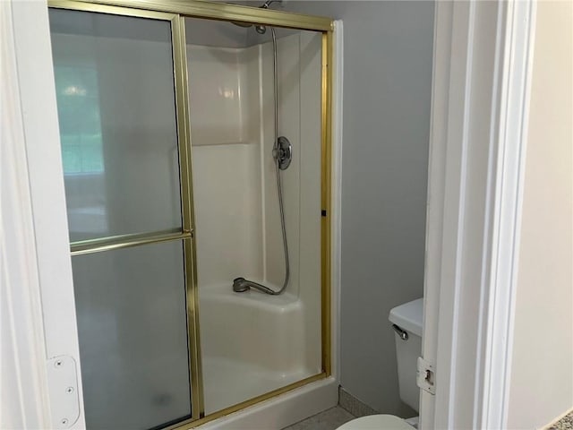 bathroom with a shower with door and toilet