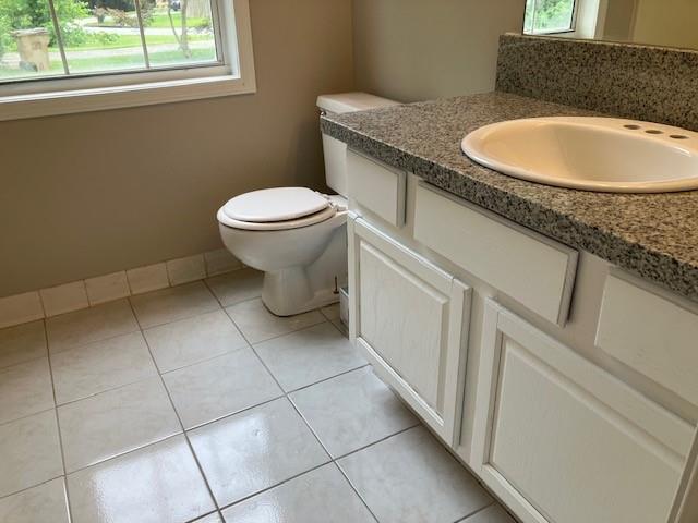 bathroom with toilet, vanity, and tile patterned flooring