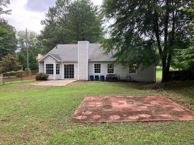 rear view of property featuring a patio and a yard