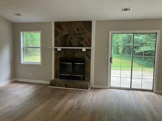 unfurnished living room with wood-type flooring and a stone fireplace