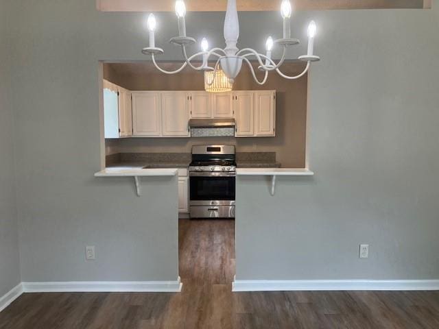 kitchen with white cabinets, a breakfast bar area, gas range, and a notable chandelier