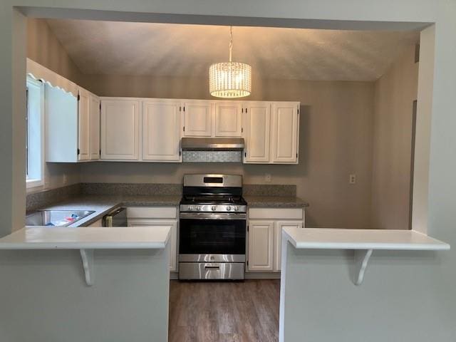 kitchen featuring gas range, a kitchen breakfast bar, white cabinets, and kitchen peninsula