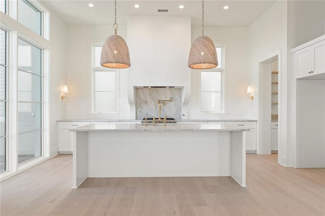 260 Guild Ln, Fayetteville, GA 30214 - kitchen featuring a kitchen island with sink, backsplash, light wood-type flooring, and white cabinetry