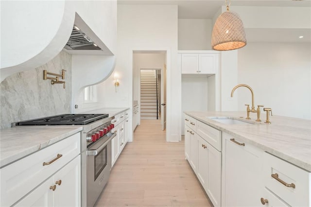 260 Guild Ln, Fayetteville, GA 30214 - kitchen featuring stainless steel range, light stone countertops, a sink, light wood finished floors, and white cabinetry