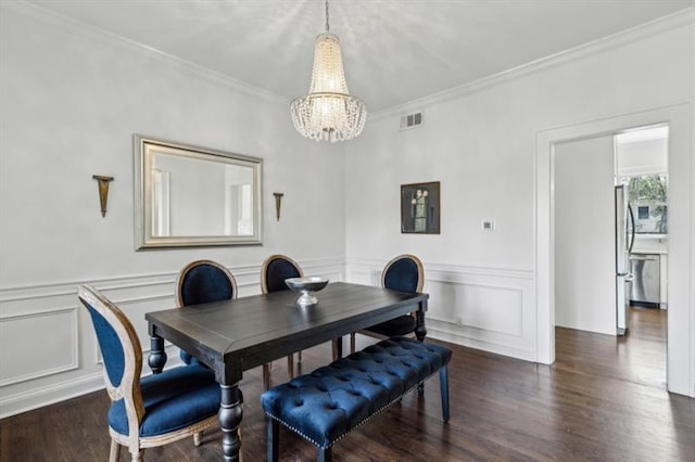 dining area featuring dark wood-style flooring, crown molding, visible vents, a chandelier, and a decorative wall
