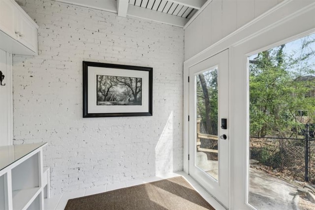 entryway with beamed ceiling and brick wall
