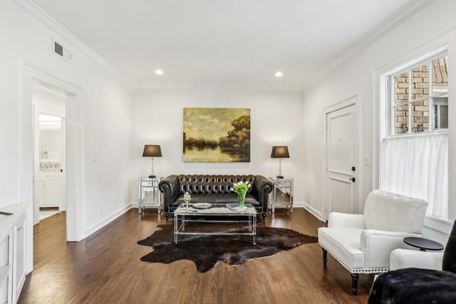 living area featuring baseboards, wood finished floors, visible vents, and crown molding