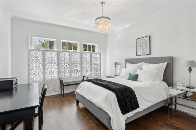 bedroom featuring wood finished floors, crown molding, and a notable chandelier