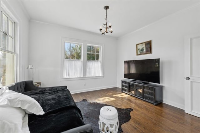 living area featuring baseboards, ornamental molding, wood finished floors, and a chandelier