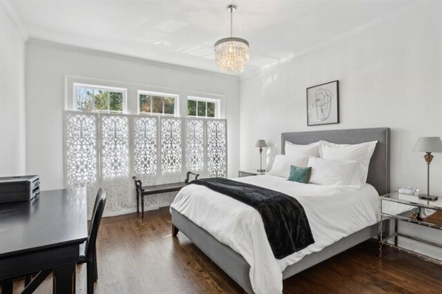 bedroom featuring wood finished floors, crown molding, and a notable chandelier