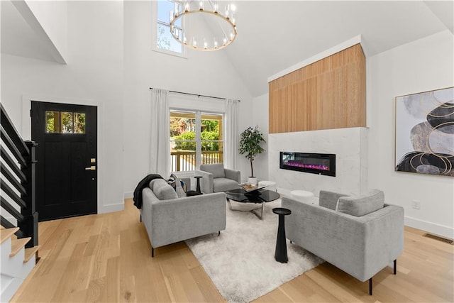 living room with a notable chandelier, high vaulted ceiling, and light wood-type flooring