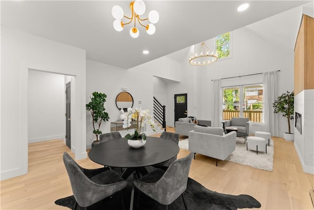 dining area featuring light hardwood / wood-style floors, a notable chandelier, and high vaulted ceiling