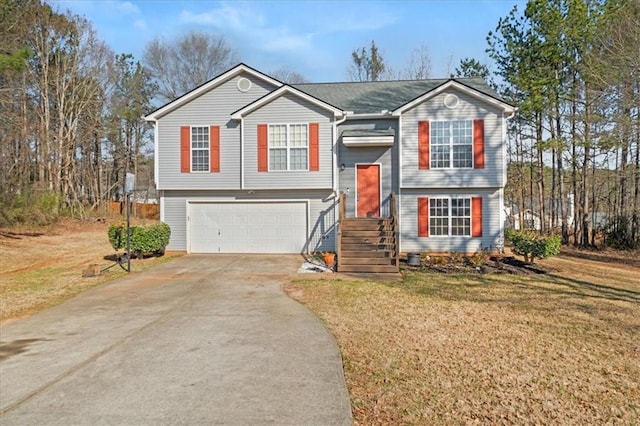 raised ranch featuring driveway, an attached garage, and a front lawn