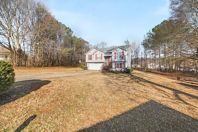 bi-level home with driveway, an attached garage, and a front lawn