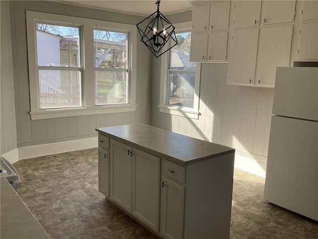 kitchen featuring hanging light fixtures, a kitchen island, white fridge, and white cabinets