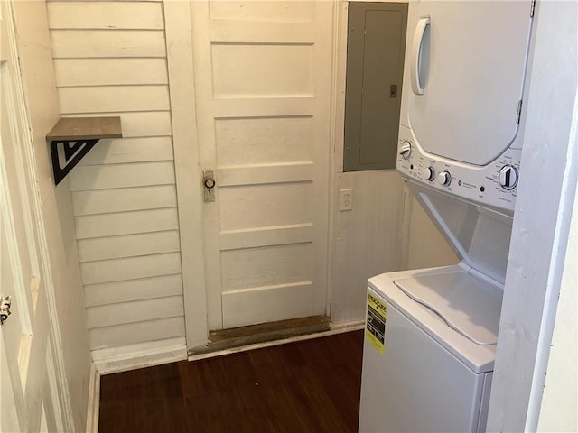 washroom with dark wood-type flooring, electric panel, and stacked washer / dryer