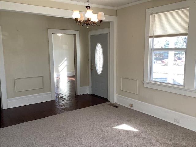 carpeted entryway featuring ornamental molding and a chandelier