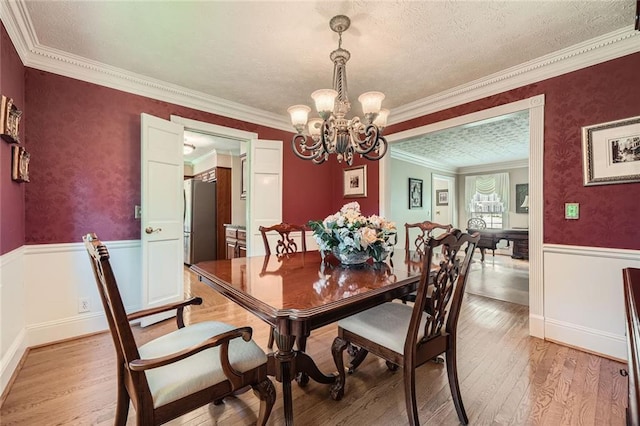 3592 Midvale Cv, Tucker, GA 30084 - dining room with wainscoting, a chandelier, crown molding, light wood finished floors, and a textured ceiling