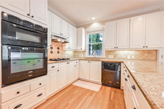 kitchen featuring sink, tasteful backsplash, light hardwood / wood-style flooring, white cabinetry, and black appliances