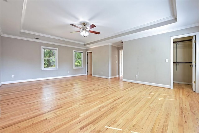 unfurnished room with ceiling fan, light wood-type flooring, a raised ceiling, and ornamental molding