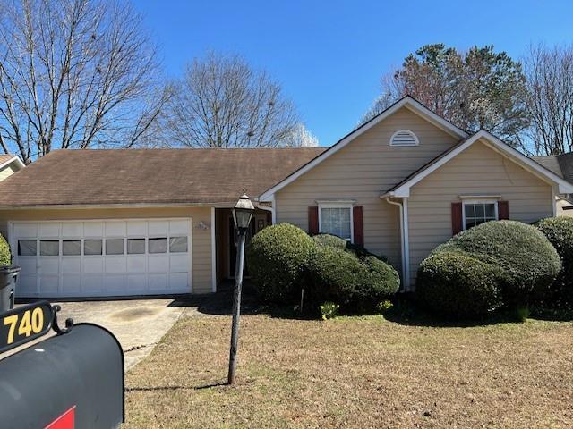 ranch-style home featuring an attached garage, driveway, and a front lawn