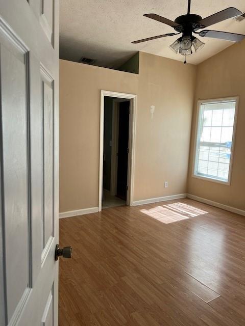 empty room featuring ceiling fan, a textured ceiling, baseboards, and wood finished floors