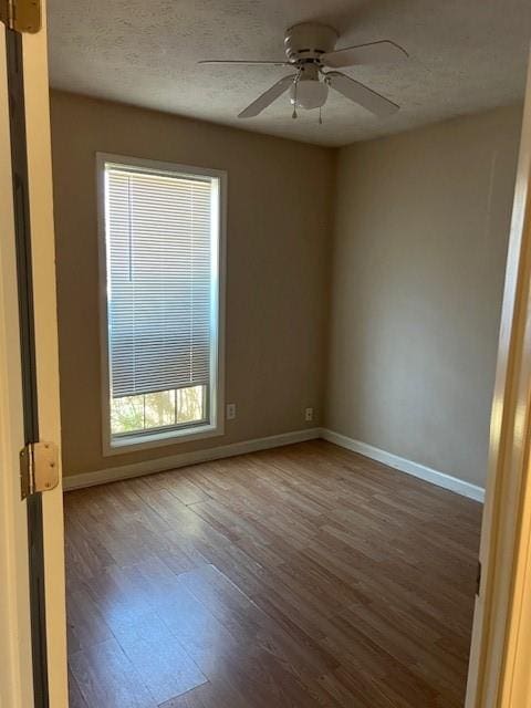 spare room featuring ceiling fan, a textured ceiling, baseboards, and wood finished floors