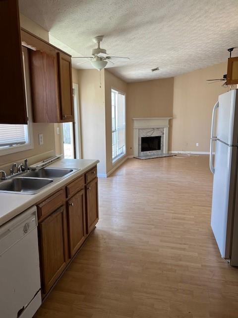 kitchen featuring white appliances, a fireplace, a ceiling fan, and a sink